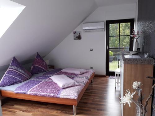 a bedroom with a bed with purple pillows and a kitchen at Ferienwohnung Orchidee in Bad Münstereifel