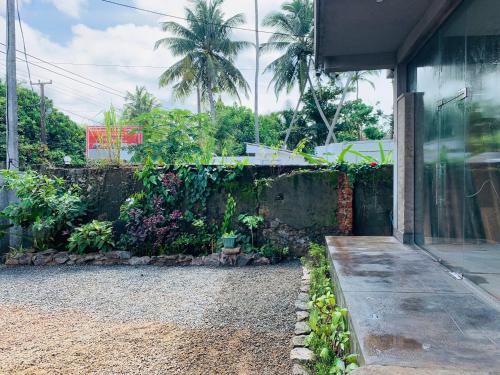 a house with a stone wall and a garden at Mirage Beach House at Morava Court in Hikkaduwa