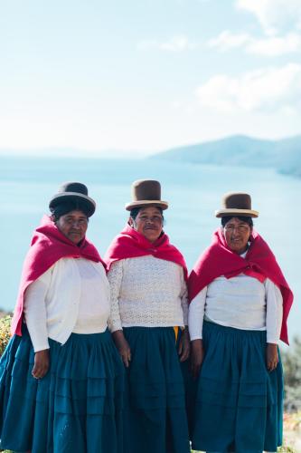 three older women wearing hats and skirts posing for a picture at Ecolodge La Estancia in Comunidad Yumani