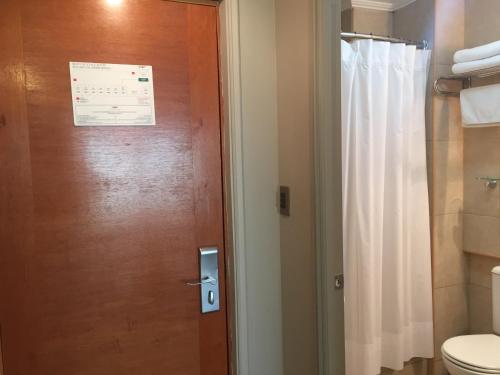 a bathroom with a toilet and a door with a sign on it at OHiggins Park Hotel in Valparaíso