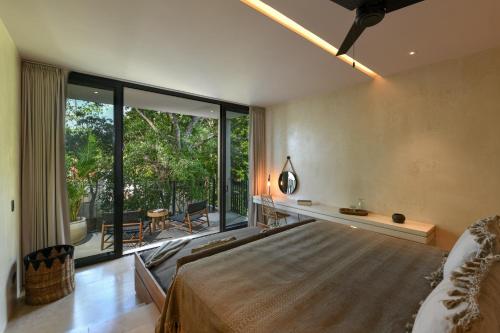 a bedroom with a large bed and a large window at Casa Agape Hotel Tulum with Beach Club Access in Tulum
