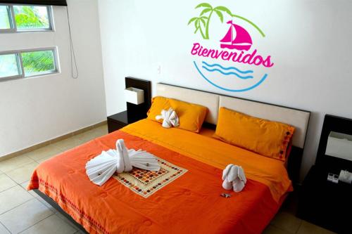 1 dormitorio con 1 cama grande de color naranja y toallas. en Playa Kas, en Playa del Carmen