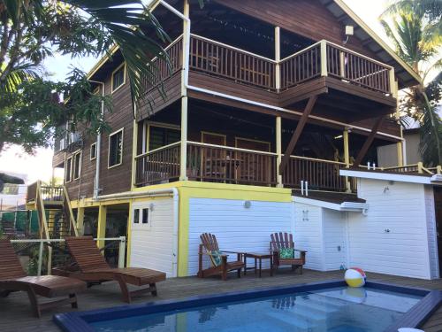 a house with a balcony and a swimming pool at Driftwood Gardens Guesthouse in Placencia Village