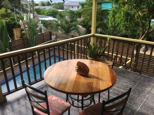 a wooden table and chairs on a balcony with a pool at Driftwood Gardens Guesthouse in Placencia Village