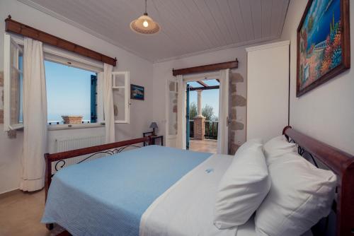 a bedroom with a bed with white pillows and a window at Ionian Villas in Volimes
