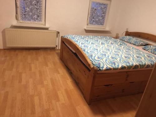 1 dormitorio con 1 cama, suelo de madera y 2 ventanas en Haus Hennecke, en Lennestadt