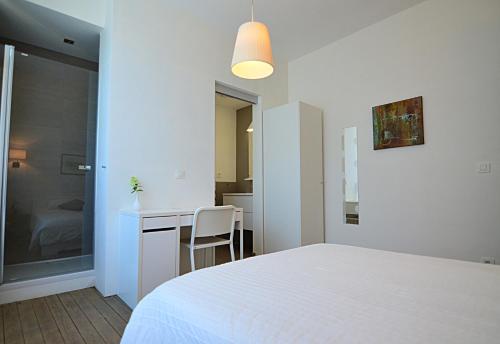 a bedroom with a white bed and a desk at La Citadine in Neufchâteau