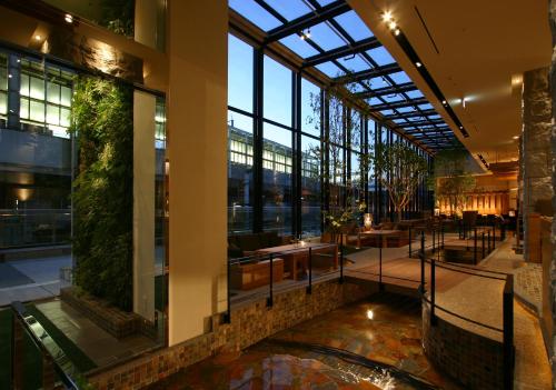 a lobby with a large glass ceiling and tables at Hotel Coco Grand in Takasaki