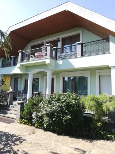 a large white house with a balcony at Édenkert Apartman in Keszthely