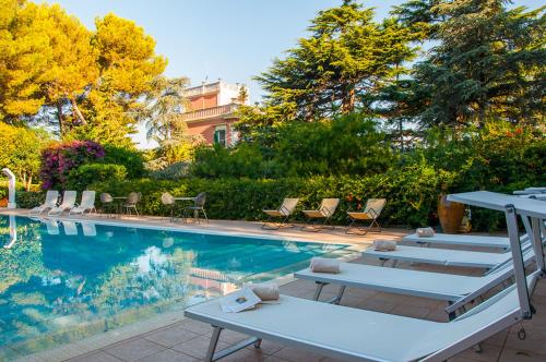 uma piscina com espreguiçadeiras e cadeiras ao lado em Villa Carenza em Monopoli