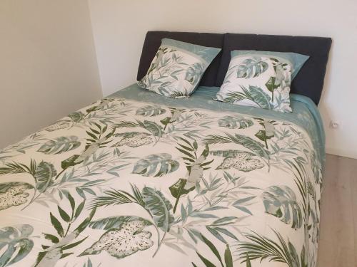 a bed with a green and white comforter and pillows at Chez marie poppins in Rozérieulles