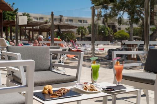 einen Tisch mit einem Teller Essen und zwei Getränken in der Unterkunft Los Zocos Impressive Lanzarote in Costa Teguise