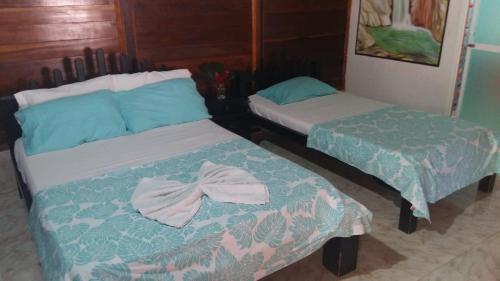 two beds in a room with towels on them at Hostal Recuerdos del Tayrona in El Zaino