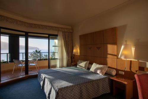 a hotel room with a bed and a balcony at Monte Mar Palace Hotel in Ponta Delgada