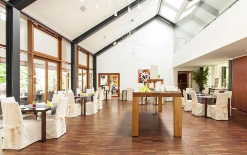 a dining room with white chairs and tables and windows at Romantik Hotel Johanniter-Kreuz in Überlingen