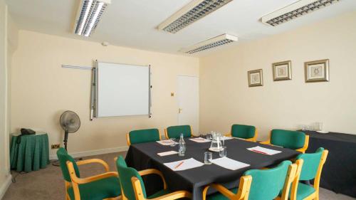 a conference room with a table and green chairs at Hotel Wrexham in Wrexham