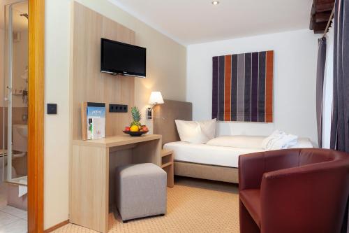 ein Hotelzimmer mit einem Bett und einem TV in der Unterkunft Romantik Hotel Johanniter-Kreuz in Überlingen