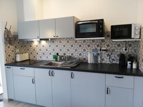 a kitchen with white cabinets and a sink and a microwave at Lopes Apartment - Belch1952 in Lagos