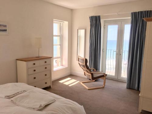 a bedroom with a bed and a chair and windows at Seacroft in Woolacombe