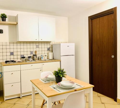 una cucina con un tavolo in legno e mobili bianchi di La Dimora della Cattedrale a Palermo