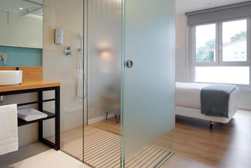 a glass shower in a bathroom with a bed at Heredad de Unanue in Donostia-San Sebastián