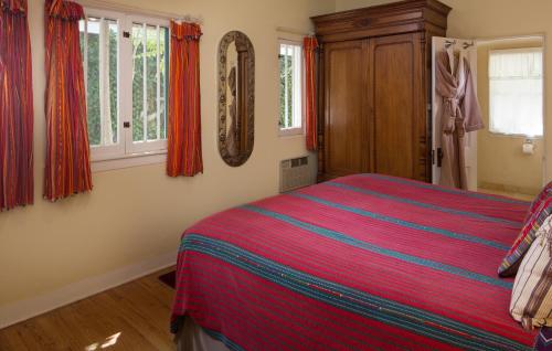 a bedroom with a bed and windows with red curtains at Casa Blanca Inn and Suites in Farmington
