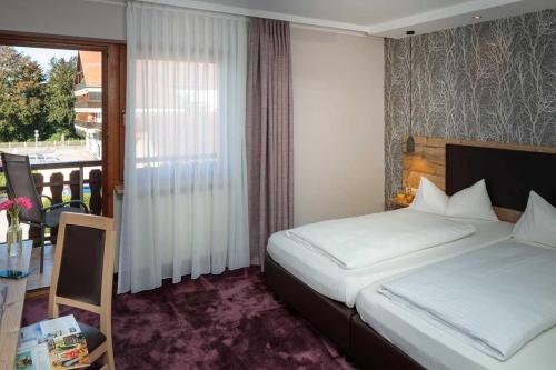 a bedroom with a bed and a table and a window at Hotel Pockinger Hof in Pocking