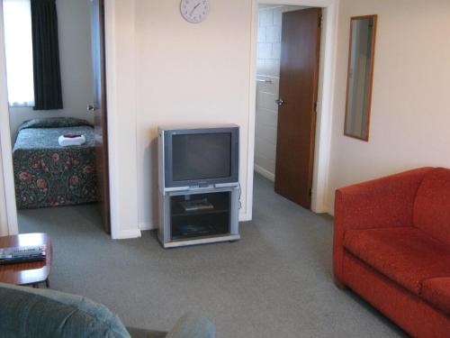 a living room with a tv and a red couch at Blue Dolphin Motel in Timaru