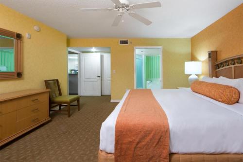 Cape Canaveral Beach Resort في كيب كانافيرال: غرفة فندقية بسرير كبير وكرسي