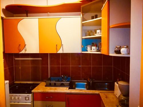 eine Küche mit orangefarbenen und weißen Schränken und einem Waschbecken in der Unterkunft Nexus Holiday in Miercurea Ciuc