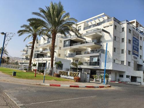a large apartment building with palm trees in front of it at Barak Royal suites VIP 46 - חמש דקות מהים ומהטיילת in Eilat