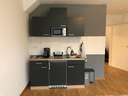 a small kitchen with black cabinets and a sink at Newtown Apartments Bremen in Bremen