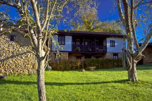 a house in a field with trees in front of it at Casa Rural La Retuerta in Nava