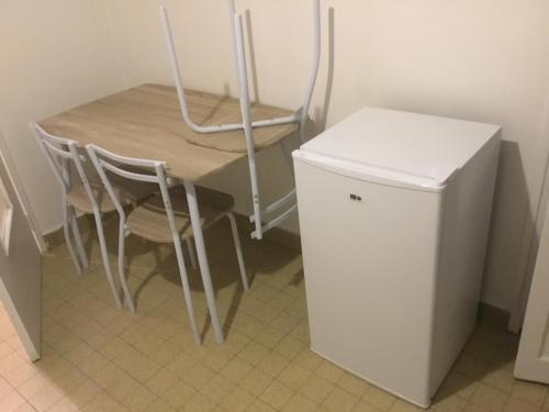 une table et des chaises à côté d'un petit réfrigérateur dans l'établissement Appart du centre, à Saint-Étienne