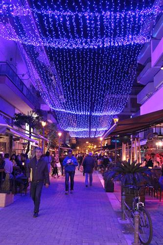 Un gruppo di persone che camminano per una strada con luci blu di SUNNY CENTRAL LUXURY APARTMENT a Volos