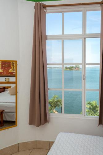 a bedroom with a window with a view of the ocean at Hotel Casa Amelia in Flores