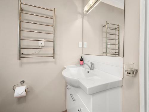 a white bathroom with a sink and a mirror at Heathcote Cottage - Taupo Holiday Home in Taupo