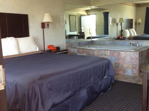 a hotel room with a bed and a bath tub at Del Amo Inn in Torrance