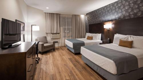 a hotel room with two beds and a flat screen tv at Best Western Plus Montreal East in Montréal