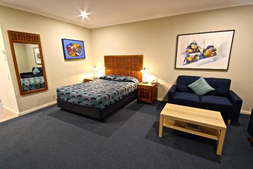 a bedroom with a bed and a couch and a chair at Bunbury Motel and Apartments in Bunbury