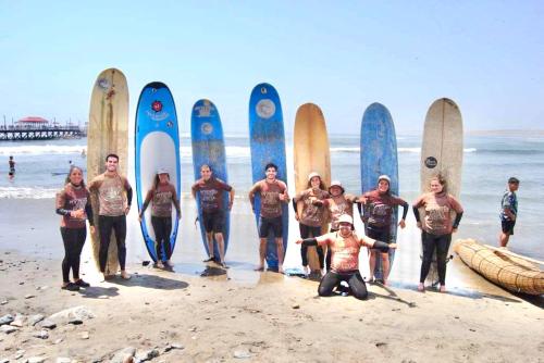 a group of people standing on the beach with surfboards at My Friend Surf Hostal in Trujillo