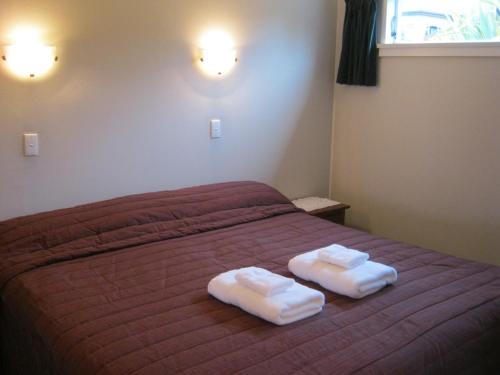 a bedroom with a bed with two towels on it at Blue Dolphin Motel in Timaru