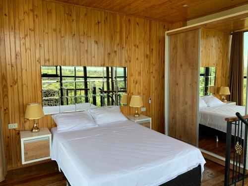 a bedroom with a white bed and two windows at NatuCenter Hospedaje in Puerto Presidente Franco