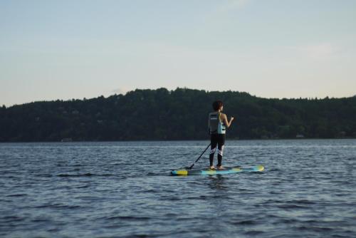 a person standing on a paddle board in the water at Nojiri Lake Resort in Shinano