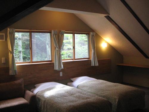 two beds in a room with two windows at La Forest De Nome Karuizawa in Karuizawa