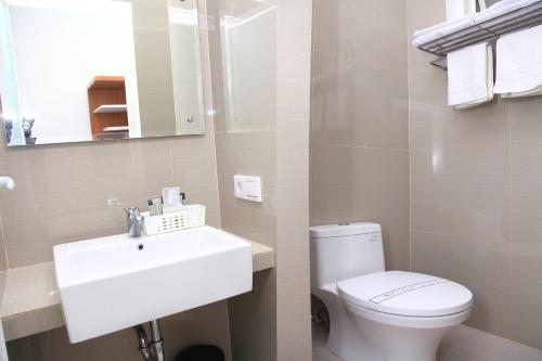 a bathroom with a white sink and a toilet at Arawa Traveller's Inn Motel in Makassar