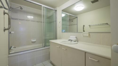 een witte badkamer met een wastafel en een douche bij Bayview Harbourview Apartments in Mooloolaba