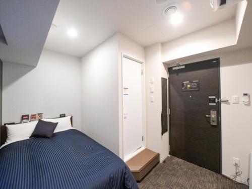 a small bedroom with a bed and a door at HOTEL LiVEMAX Asakusa-Ekimae in Tokyo