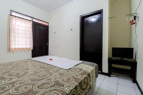 Dormitorio pequeño con cama y TV en Cempaka Hotel, en Yogyakarta