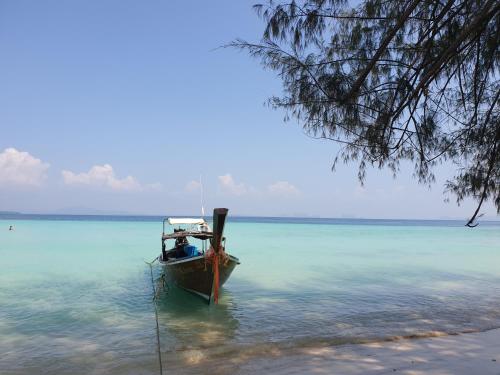 a boat sitting in the water on a beach at Aladdin Guest House in Phi Phi Don